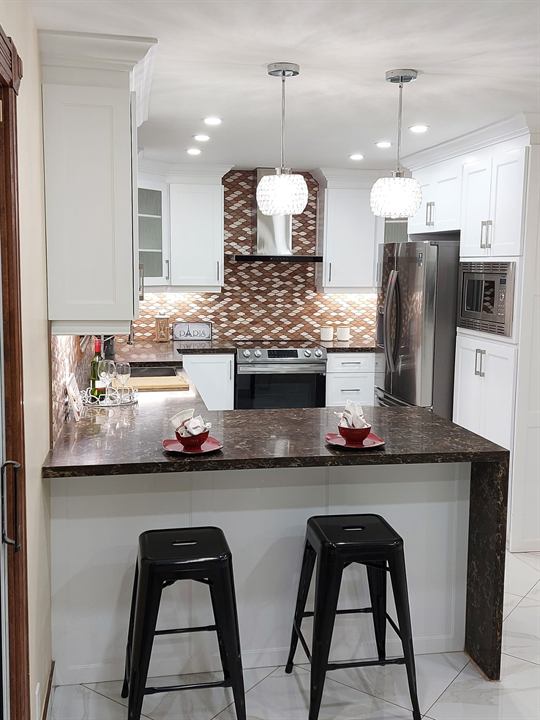 Kitchen remodel with white cabinetry, mosaic backsplash and breakfast bar