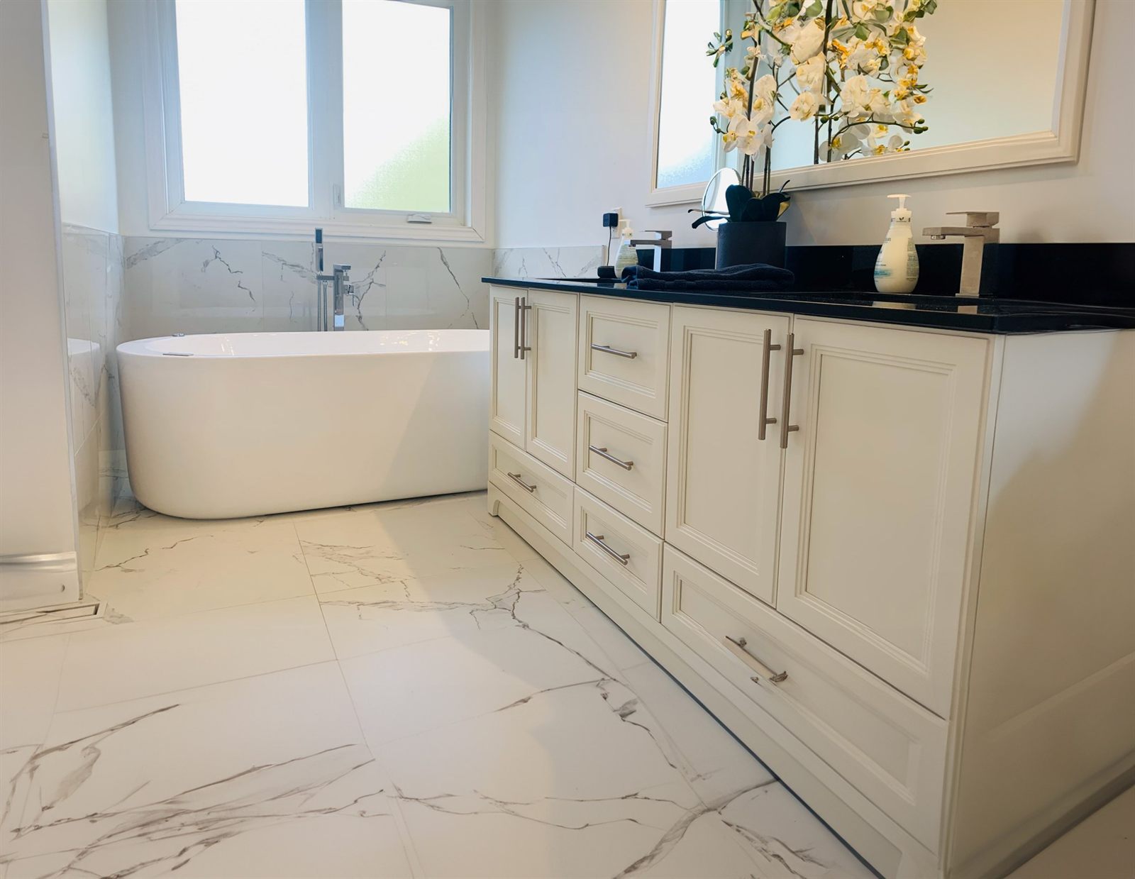 Master bathroom renovation with freestanding tub, double vanity and marble-look tile