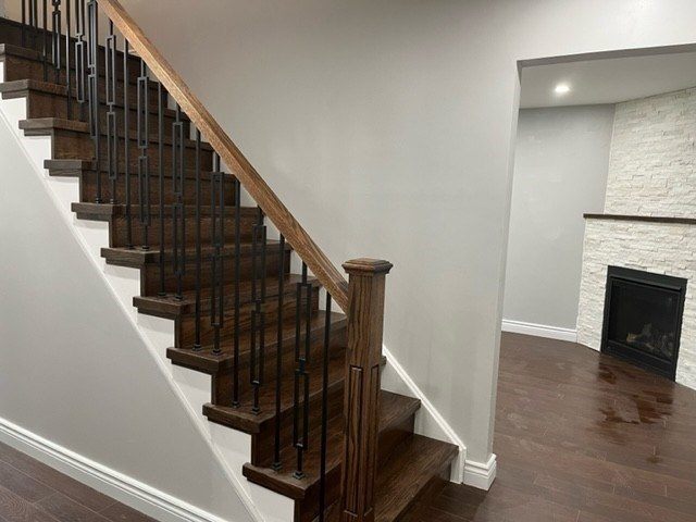 Refinished staircase with iron spindles and stone fireplace surround
